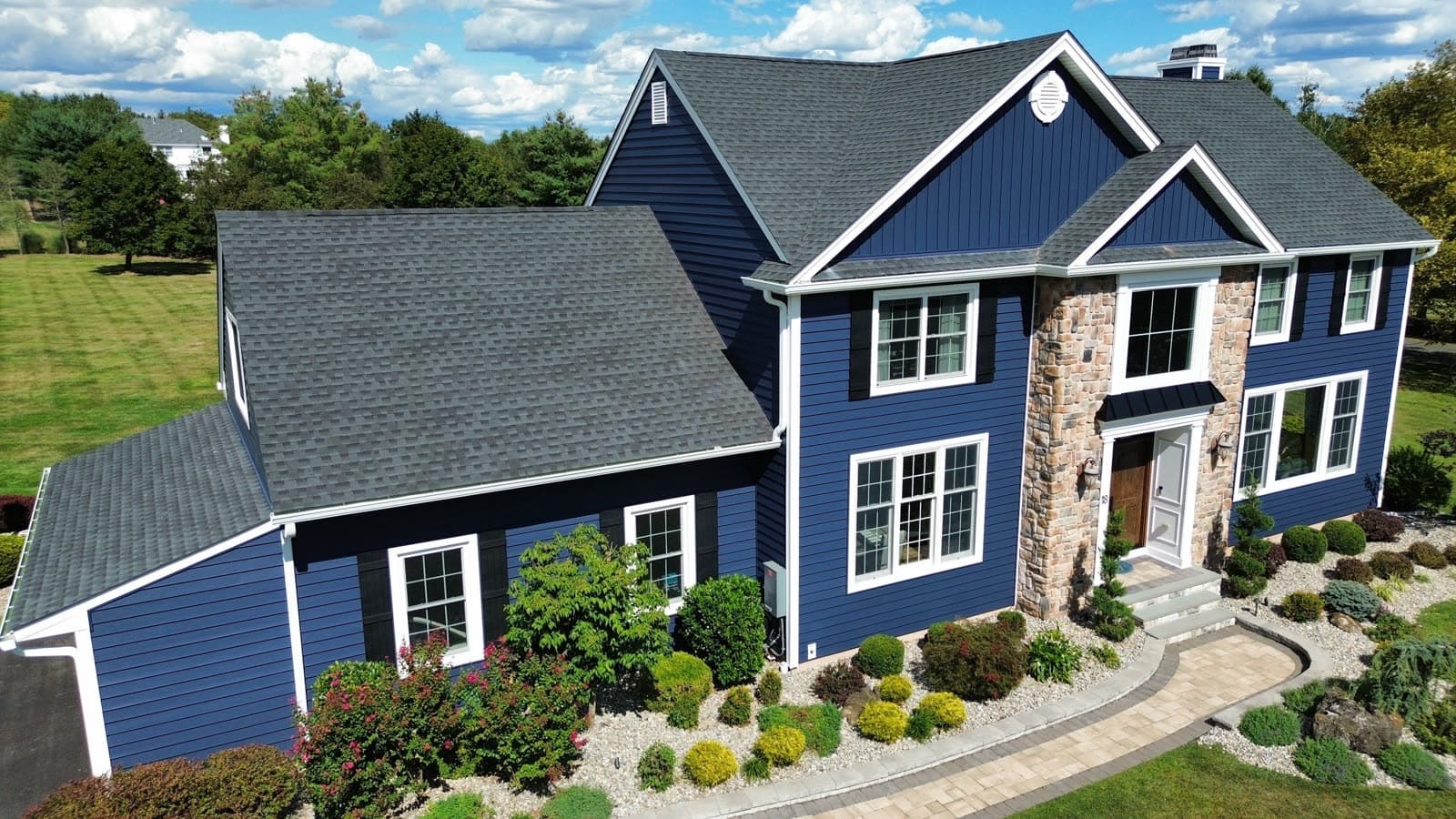 Finished navy lap and board-and-batten siding with stone surround on a New Jersey home